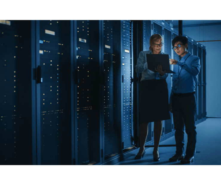 Two IT security engineers working on laptop in data centre server room during Pitman Training CompTIA Security+ diploma course