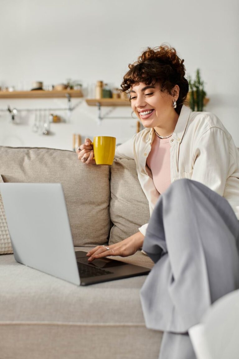Smiling student on a sofa with a laptop and coffee, showing how Pitman Training Wexford offers flexible learning that fits around work and family commitments.