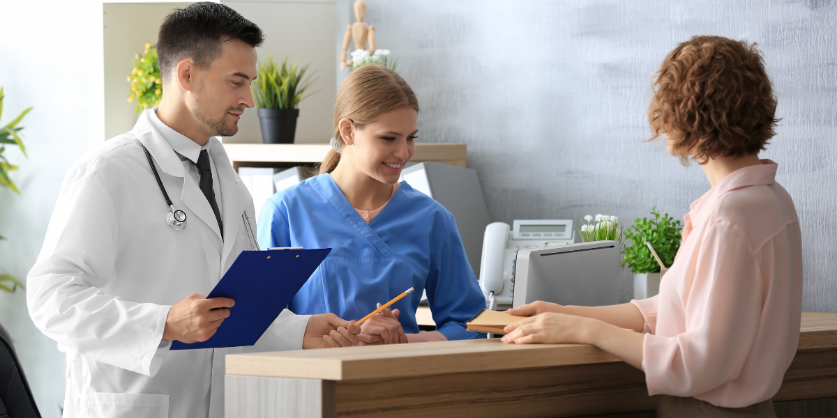 A skilled Medical Secretary in Wexford helping a doctor with patient administration at the front desk. Start your career in healthcare administration with top training.