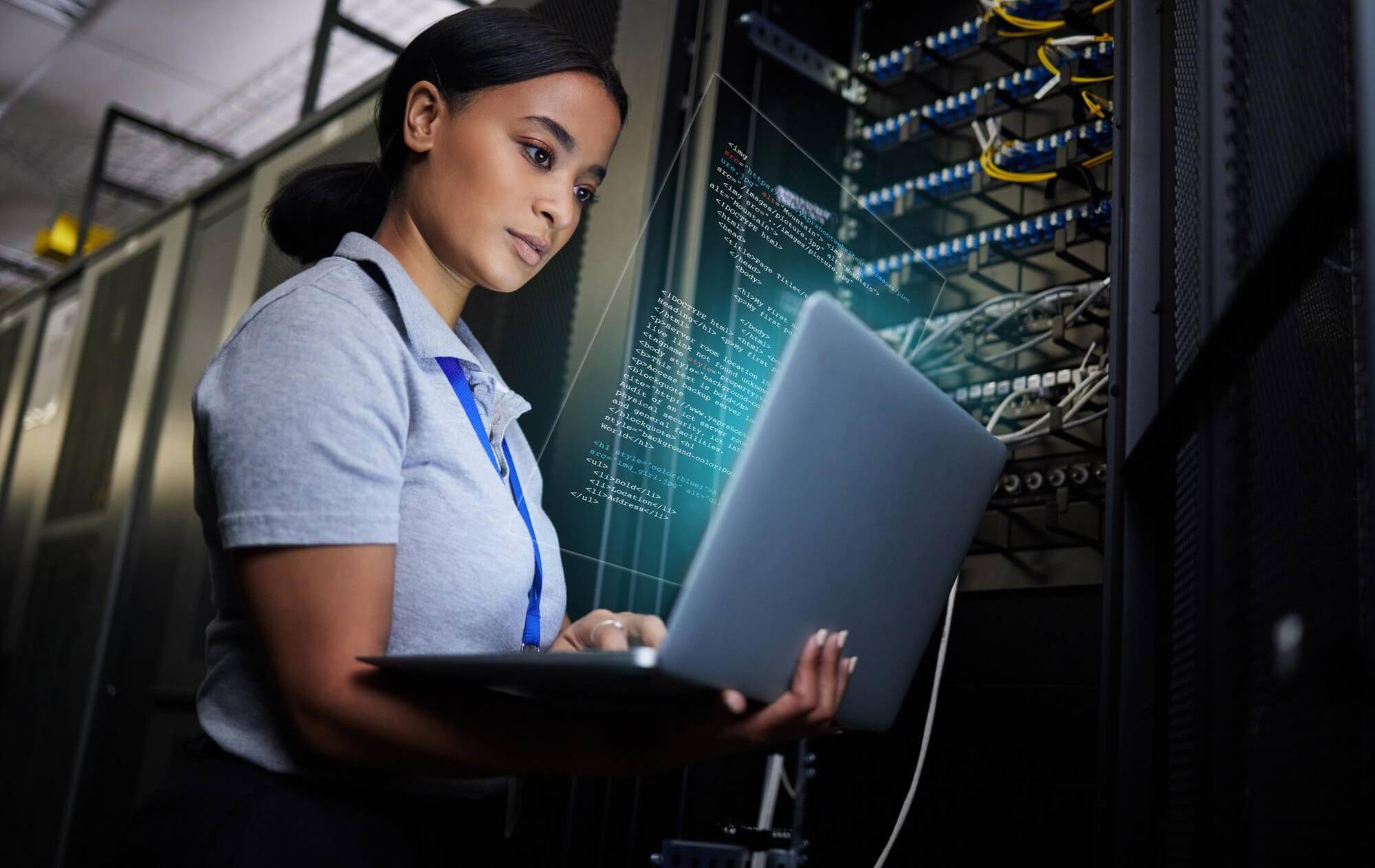 Female IT security engineer working on laptop in server room during Pitman Training CompTIA Security+ course