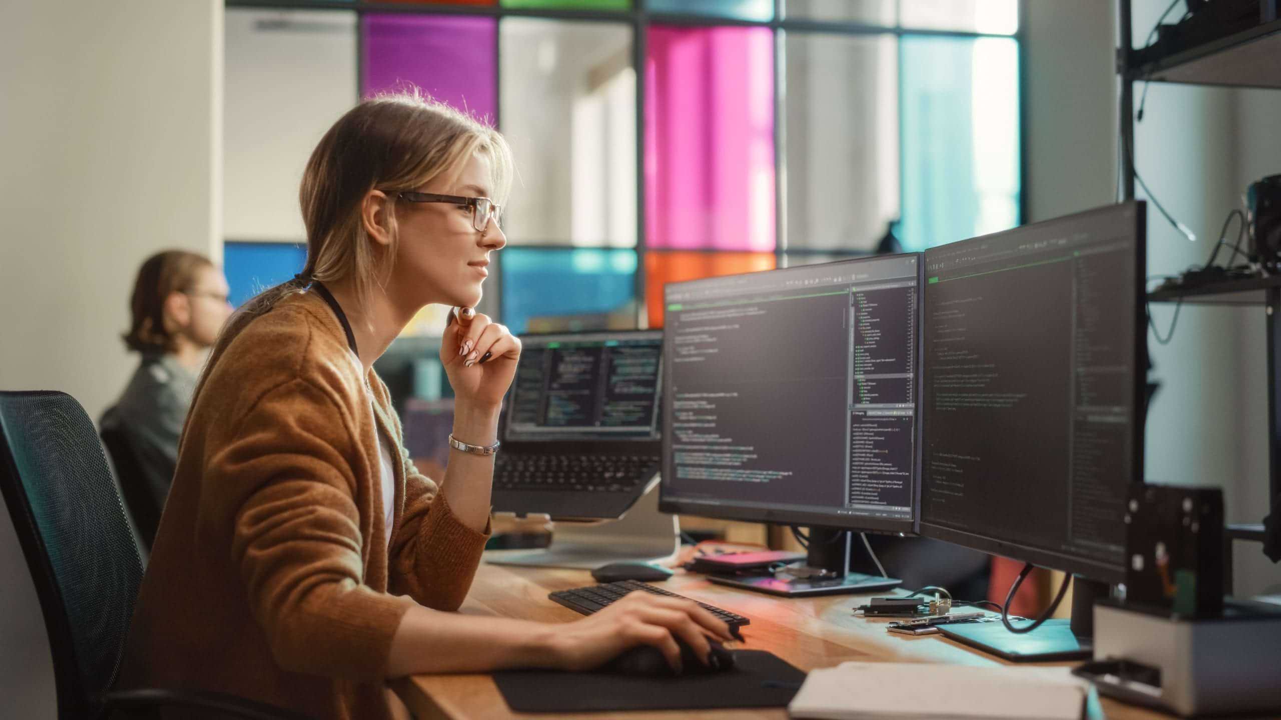 Focused student coding on dual monitors during Software Development Diploma training