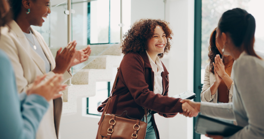 Woman smiling and shaking hands with colleagues celebrating — career progression and upskilling with Pitman Training